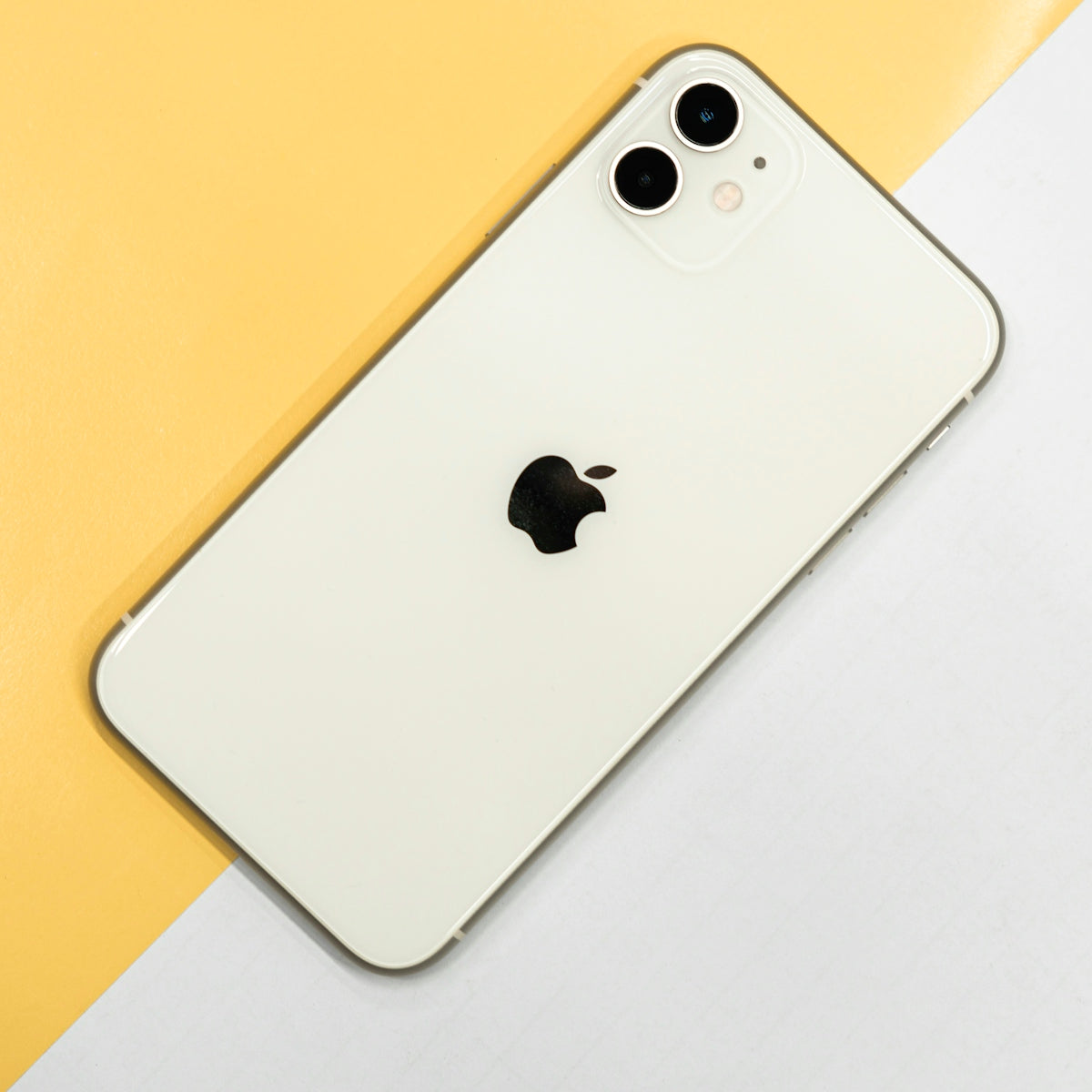 White smartphone with dual rear cameras and Apple logo on yellow and white background